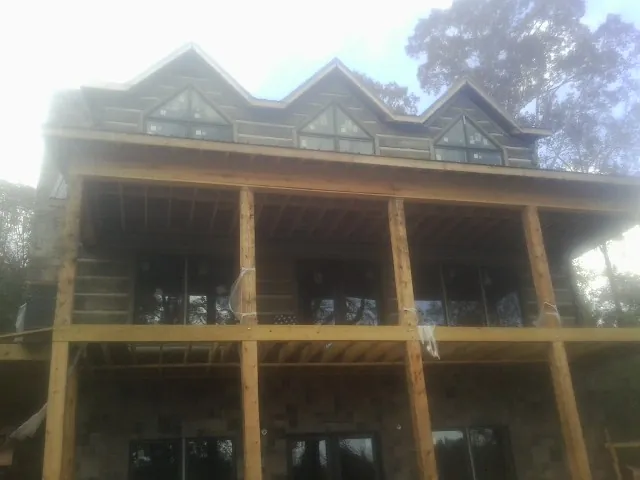 Dormers and porch framing on a large log home under construction — Roof Coating work by our crew in Yale
