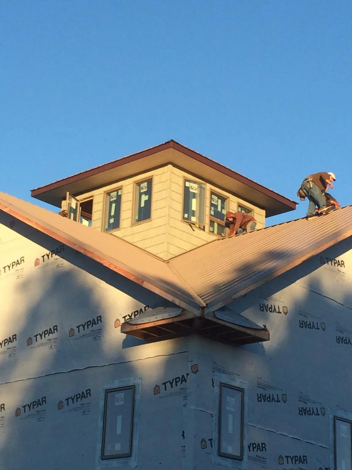 Roofers working around a rooftop cupola on a new metal roof at sunset — Roof Waterproofing in Yale by Roofing Brothers